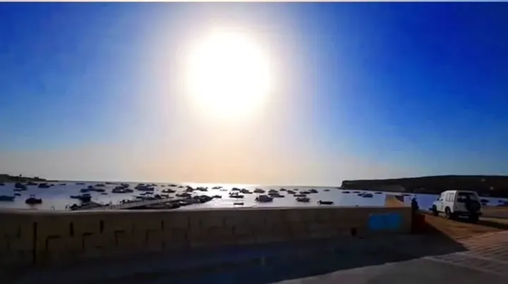 The sun shining over a calm harbour